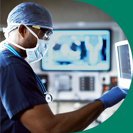 A person in full scrubs tapping a monitor display